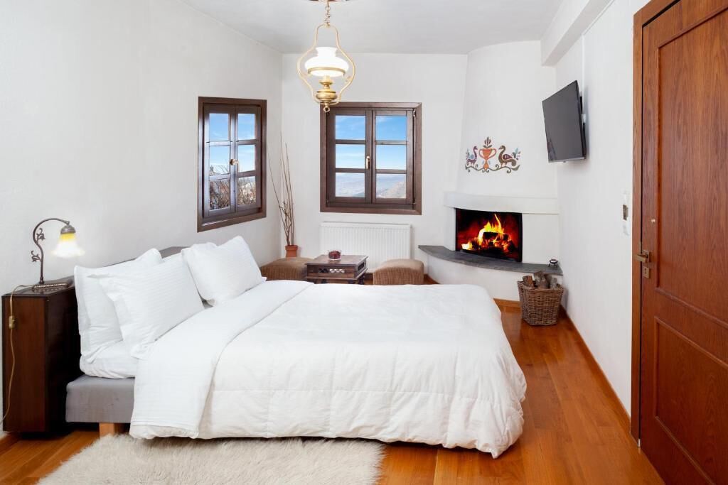 Un dormitorio con cama, chimenea, televisión y ventana.