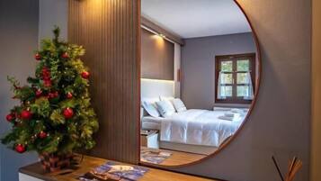 Een slaapkamer met een grote spiegel, een kerstboom en een nachtkastje met een lamp.
