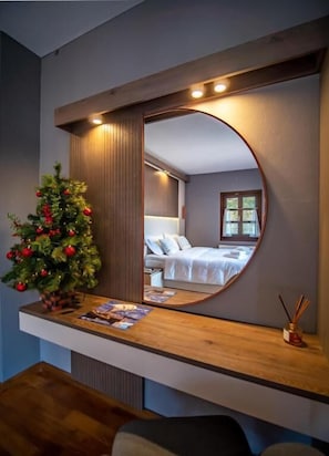 Um quarto com um espelho grande, um pinheiro de Natal e uma mesa de cabeceira com uma luminária.
