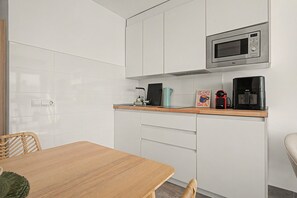 Eine moderne Küche mit weißen Schränken, einer Mikrowelle, einer Kaffeemaschine und einem Toaster.