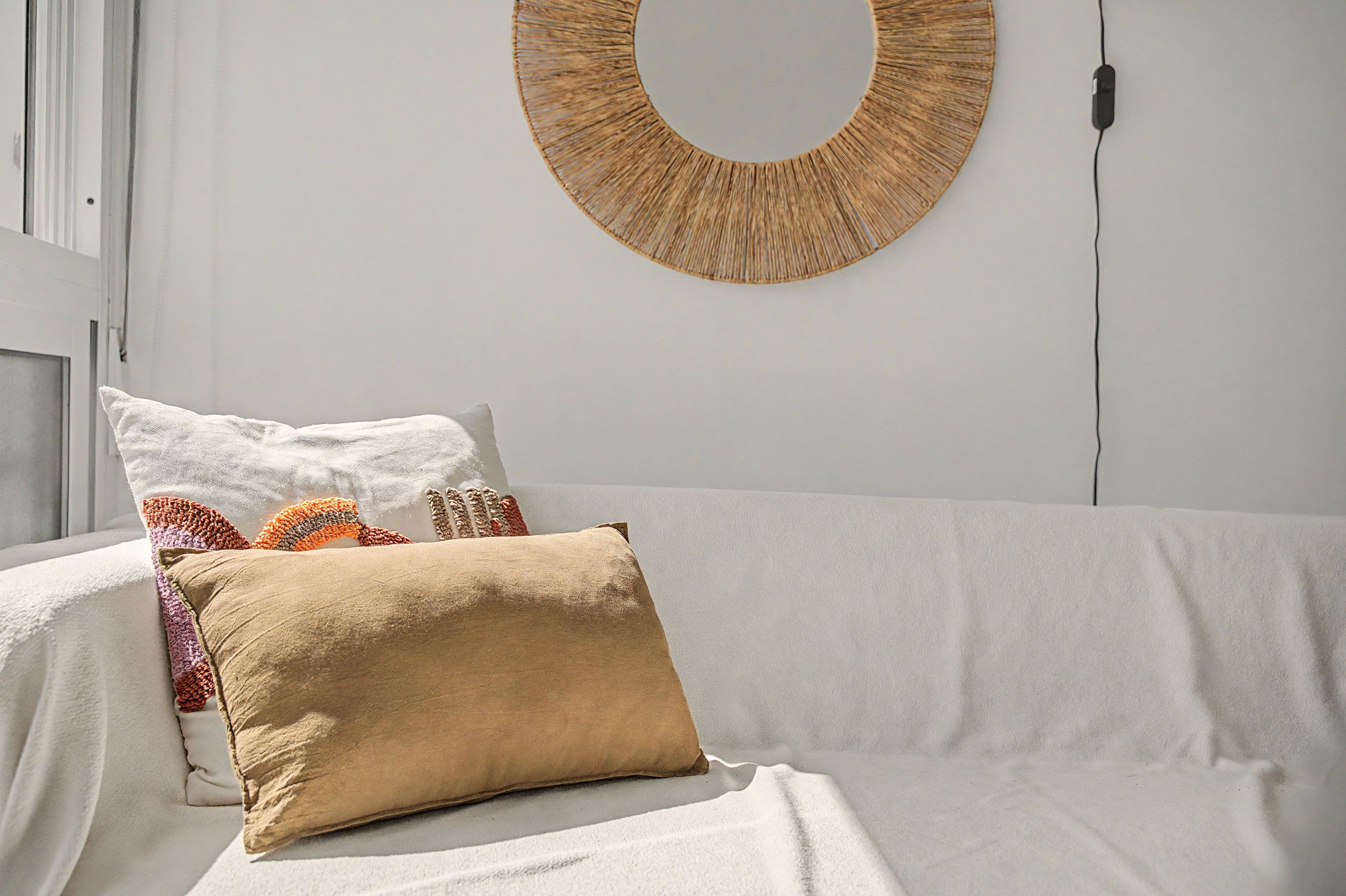 Uma cama com cobertura branca, um travesseiro bege e um travesseiro estampado.