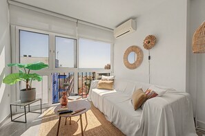 Ein modernes Wohnzimmer mit großem Fenster, einer Couch, einem Couchtisch und einer Topfpflanze.