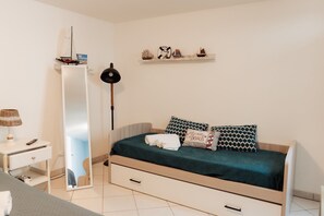 A bedroom with a bed, bedside table, lamp, and a shelf with decorative items. - Villa Tufara | Ocean View & Private Beach (San Vito)
