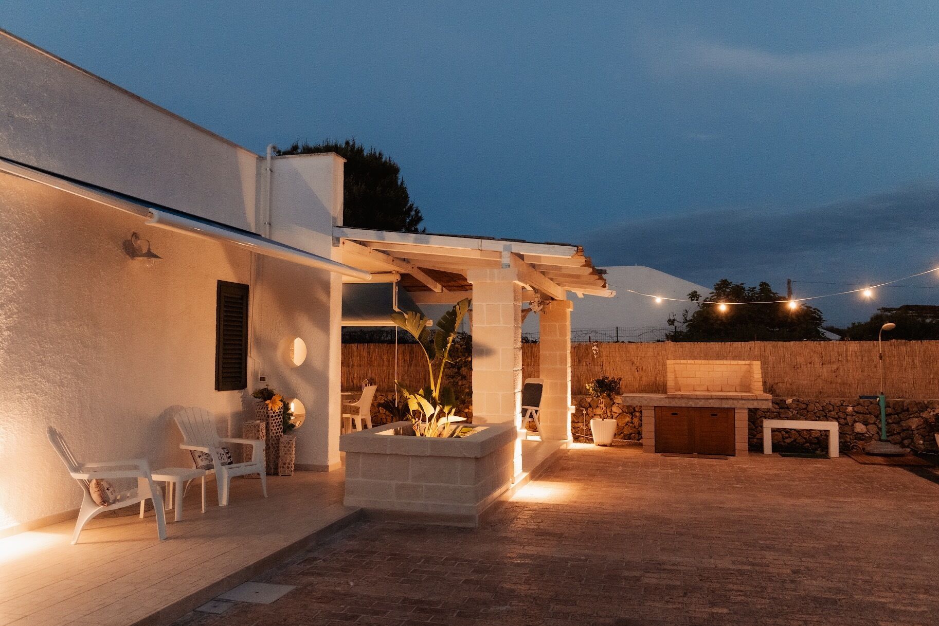 A covered outdoor patio with chairs, a fire pit, and a barbecue area.
