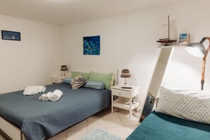 Une chambre à coucher avec un lit, deux tables de chevet, une lampe, un tableau et une petite étagère avec un livre.