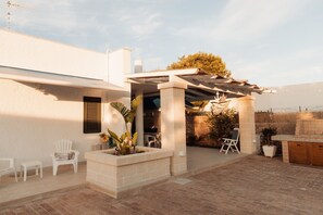 A patio area with a pergola, seating, and a brick planter. - Villa Tufara | Ocean View & Private Beach (San Vito)