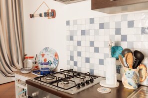 A kitchen with a gas stove, a hanging kitchen towel rack, and a tiled backsplash. - Villa Tufara | Ocean View & Private Beach (San Vito)