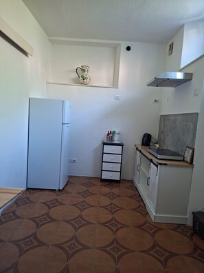 A compact kitchen with a refrigerator, a small cabinet, and a tiled floor. - A peaceful spot just a stone's throw from the Teso Forest.  
Dogs welcome. (Maresca)