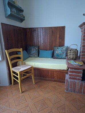 A corner room with a wooden bench, a chair, a small table with a basket, and a shelf with decorative items. - A peaceful spot just a stone's throw from the Teso Forest.  
Dogs welcome. (Maresca)