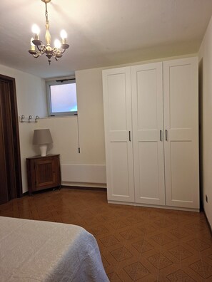 Ein Schlafzimmer mit Bett, Kleiderschrank, Fenster und einer Chandelier.