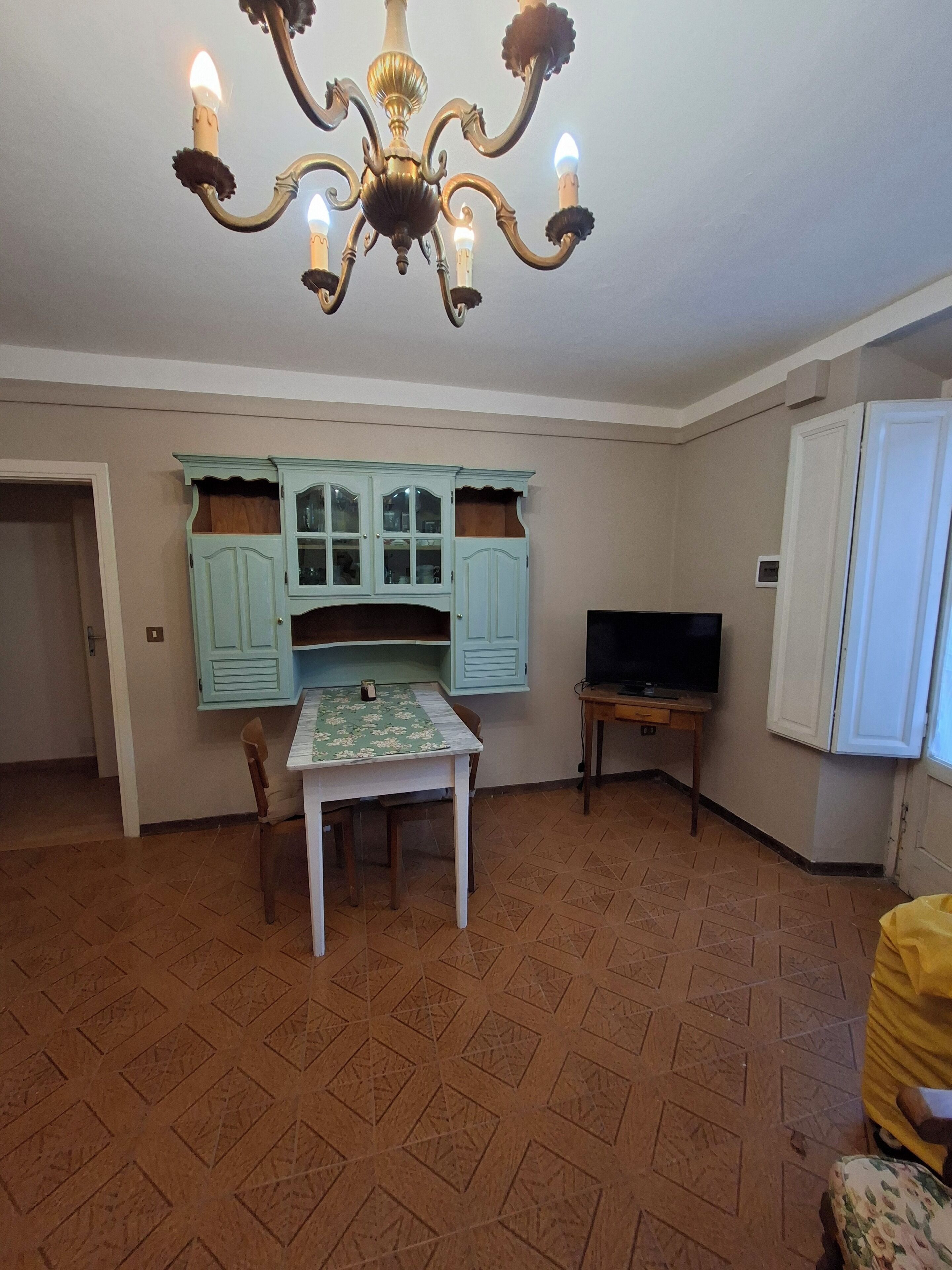 A dining area with a table and chairs, a television, and a light blue cabinet with glass doors.