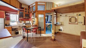 Eine kompakte Küche mit Holzausstattung, ein Essbereich mit Tisch und Stühlen sowie ein kleines Badezimmer mit Waschbecken und Spiegel.