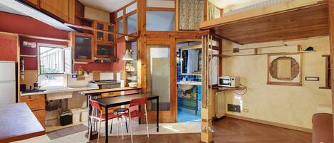 Cocina compacta con armarios de madera, comedor con mesa y sillas, y un baño pequeño con lavamanos y espejo.
