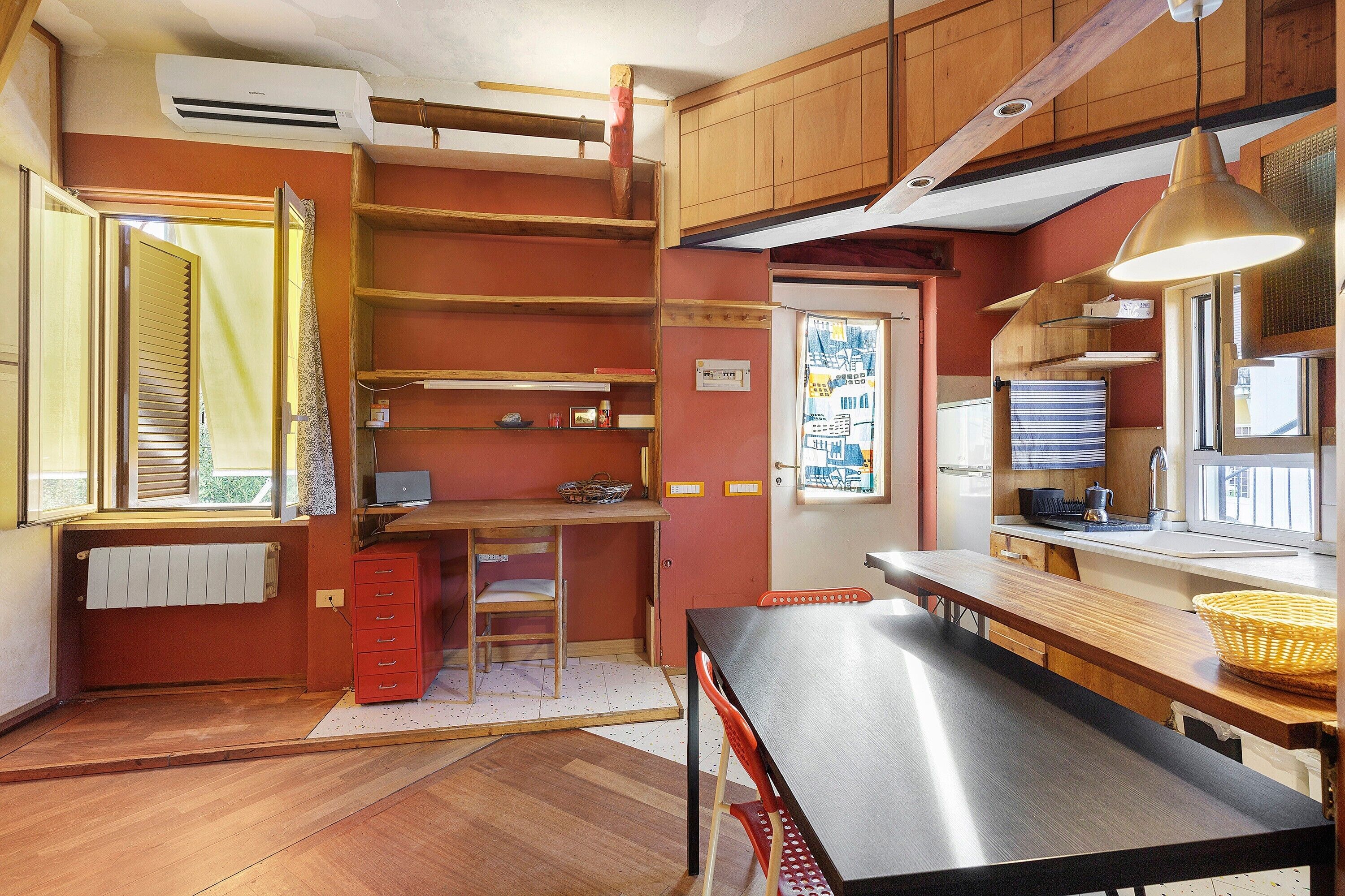 A compact kitchen with wooden cabinets, a dining table, and a window with a view.