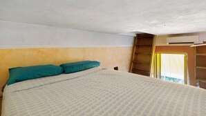 Ein Schlafzimmer mit einem Bett, zwei Kissen, einem Fenster mit Vorhängen und einer Klimaanlage.