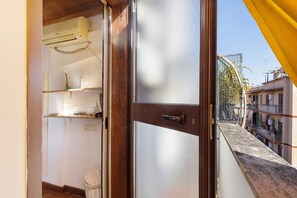 A room with a wooden door, a white wall, and a window with a yellow curtain. - Cozy Studio Near Rome Center and Transport with View (Rome)