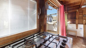 Una cucina con un fornello a gas, mobili in legno e una finestra con persiane.