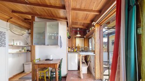 Una cucina compatta con travi in legno, un tavolo da pranzo, sedie e un frigorifero.