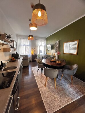 Une cuisine moderne avec un coin repas, une table ronde et un mur d’accent vert.
