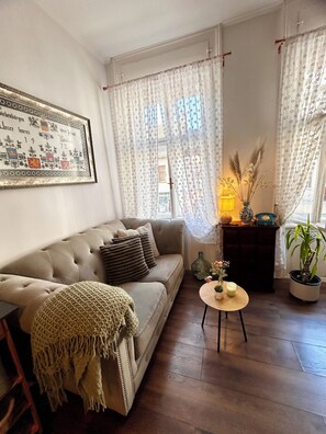 A living room with a sofa, a small round table with a candle, and a potted plant. - "Lerosa Aaluna" Old Town Boutique Apartment, Sleeps 6 (Sibiu)