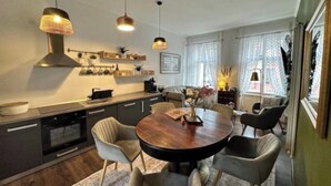 A modern kitchen with a round dining table, pendant lights, and a built-in oven. - "Lerosa Aaluna" Old Town Boutique Apartment, Sleeps 6 (Sibiu)