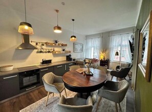 A modern kitchen with a round dining table, pendant lights, and a built-in oven. - "Lerosa Aaluna" Old Town Boutique Apartment, Sleeps 6 (Sibiu)