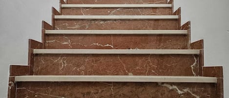 A marble staircase with a handrail leading to a doorway.