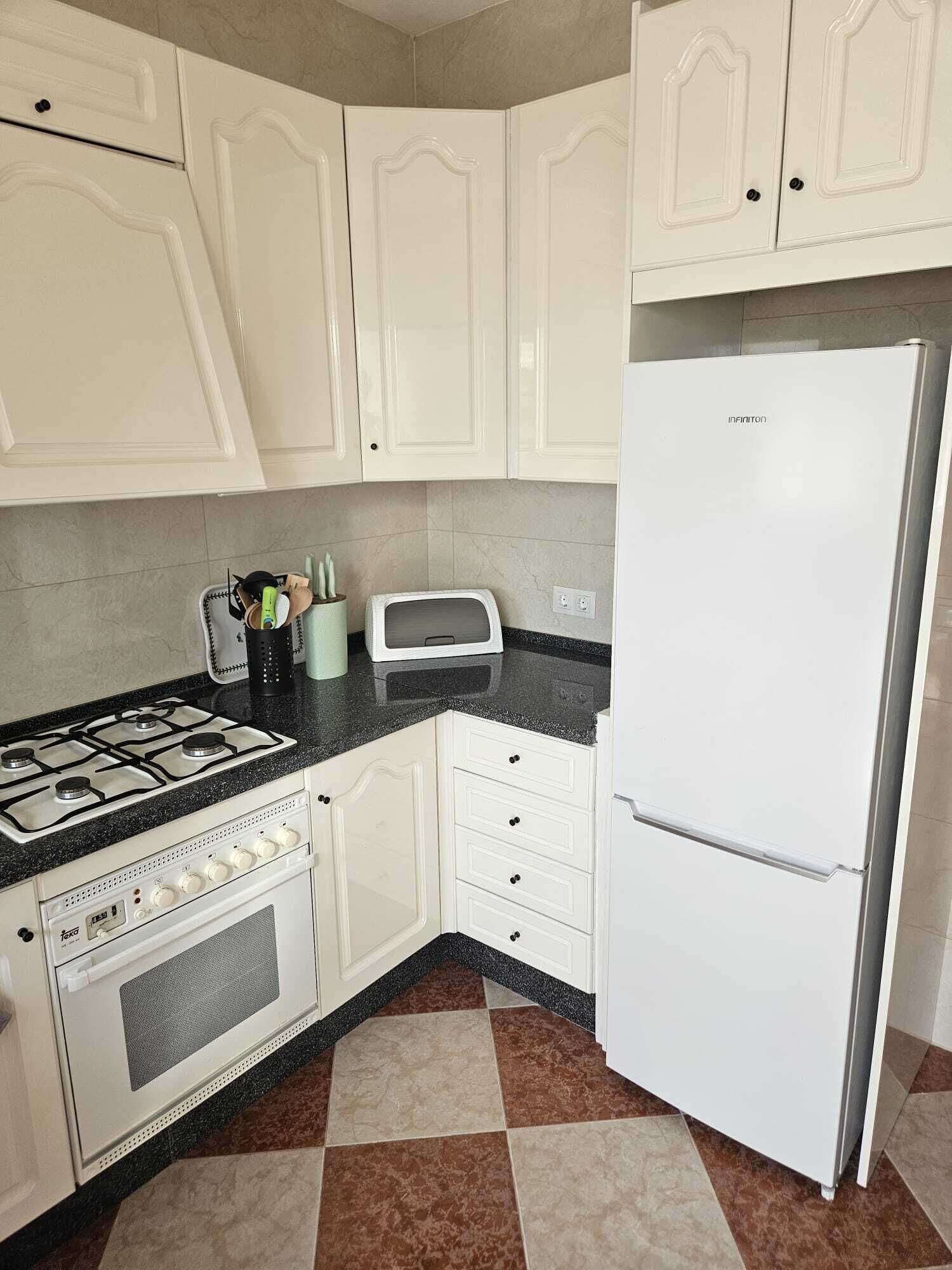 A kitchen with white cabinets, a gas stove, a microwave, and a refrigerator.