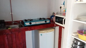 Une cuisine compacte équipée d’une cuisinière à gaz, d’un four à micro-ondes et d’un petit réfrigérateur.