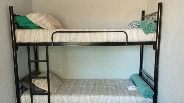 Un lit superposé à deux niveaux, avec une échelle et une couvre-lit matelassé.