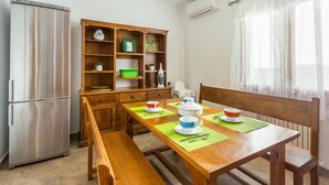 A compact kitchen with a built-in refrigerator, wooden cabinetry, and a dining table set with bowls and spoons. - Villa 'Russadir' with Private Pool, Wi-Fi and Air Conditioning (Santanyí)