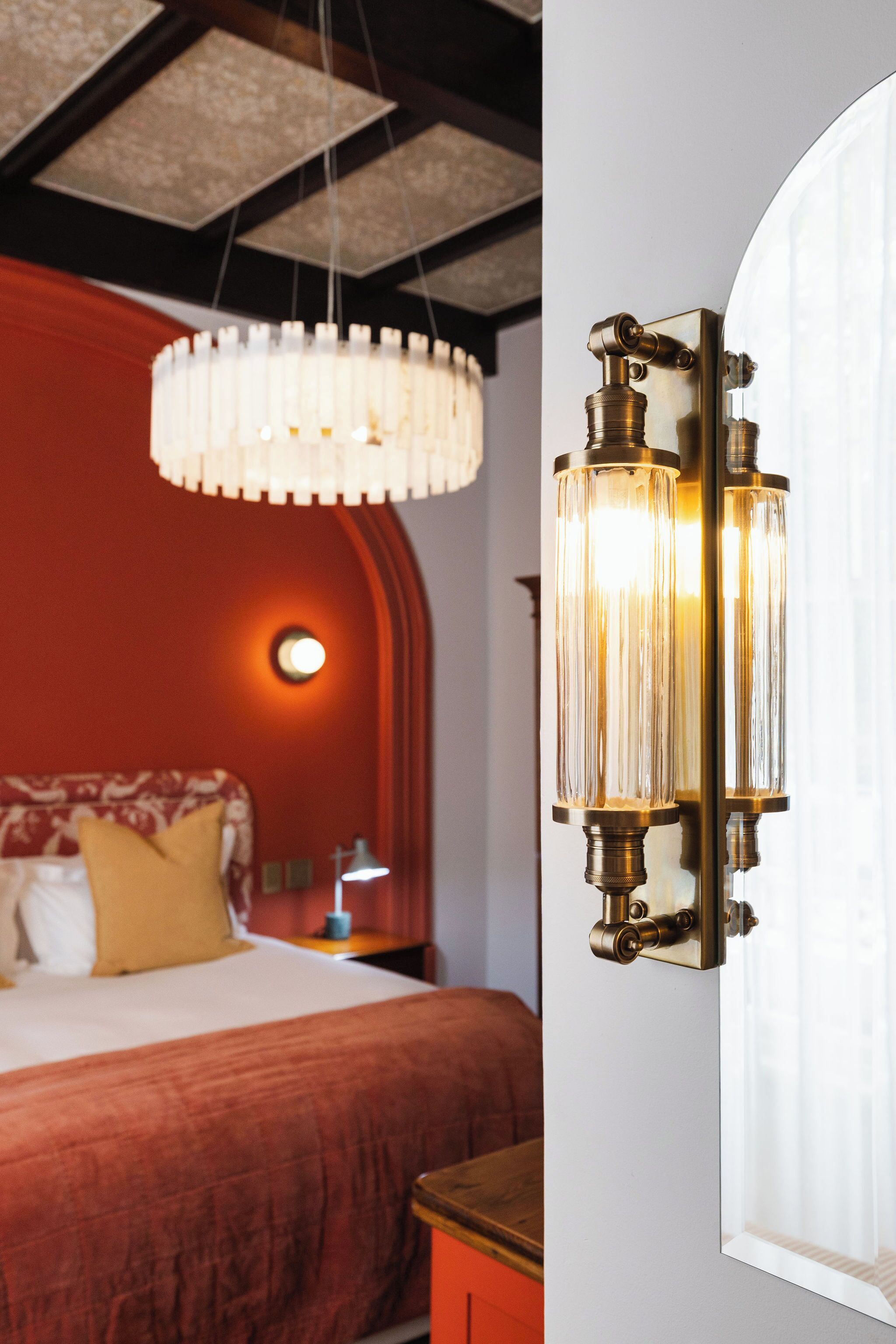 Un dormitorio con una cama, una mesita de noche, una lámpara y una lámpara de pared.
