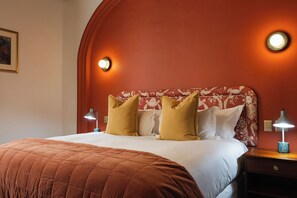 Ein Hotelzimmer mit einem Bett, zwei Nachttischlampen, einem Nachttisch und einer Wandleuchte.
