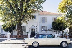 Un edificio clásico blanco con un coche negro estacionado frente a él.