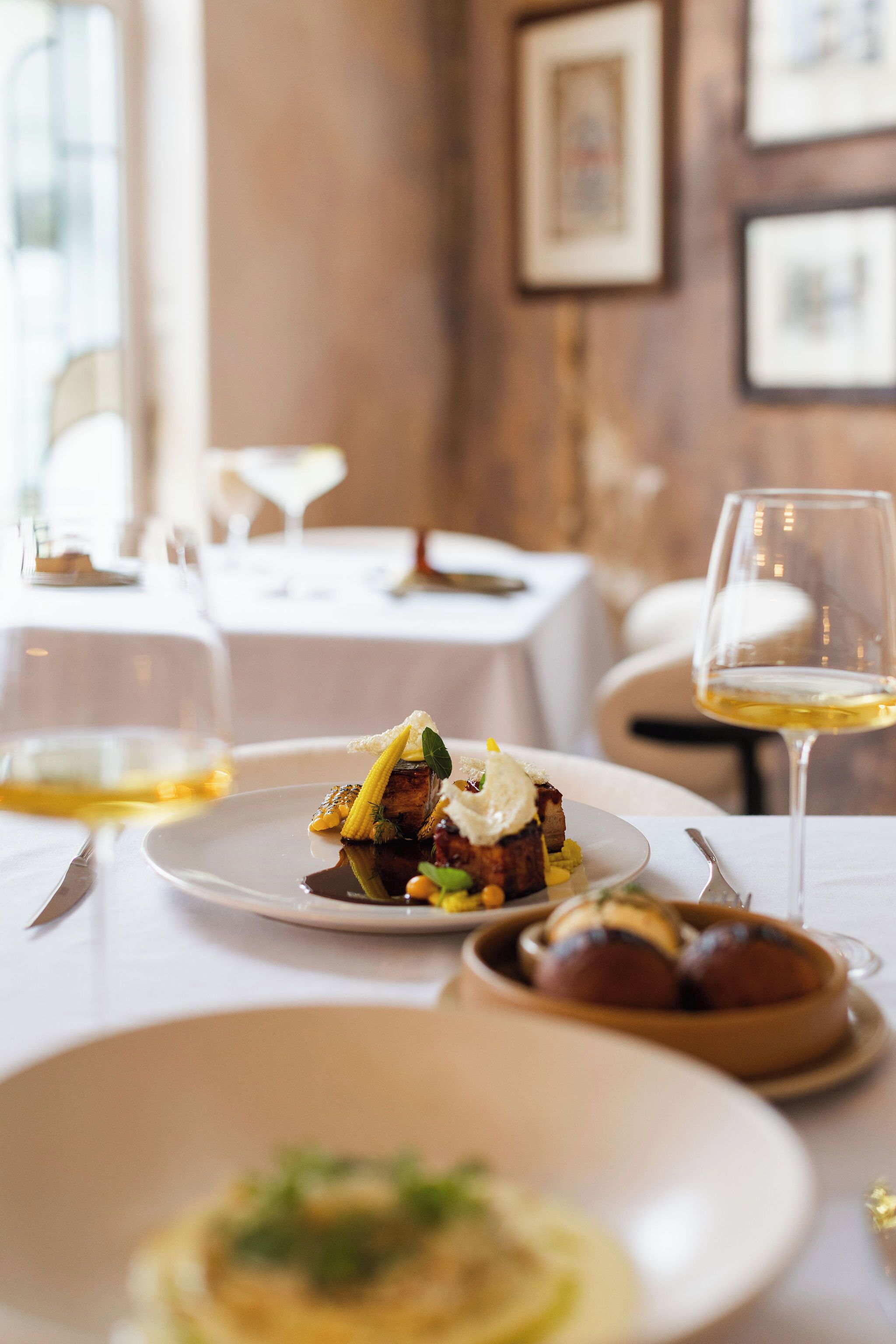 A dining table with plates of food, a wine glass, and a candle.
