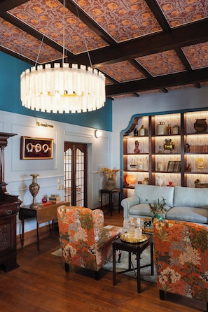 A room with a patterned ceiling, a bookshelf, a sofa, and a chandelier. - Zomerlust Boutique Hotel (Paarl)