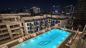 A rooftop pool with a view of a city skyline at night. - Luxury 2BR Apartment Dubai, Pool, Gym & Free Parking (Dubai)