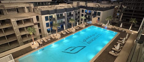 A rooftop pool with a view of a city skyline at night.