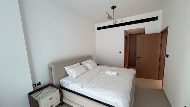 A bedroom with a bed, bedside table, wardrobe, and a ceiling light fixture. - Luxury 2BR Apartment Dubai, Pool, Gym & Free Parking (Dubai)