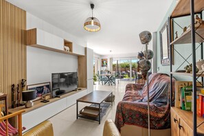 Ein modernes Wohnzimmer mit Fernseher, Sofa, Couchtisch und Dekorationselementen.