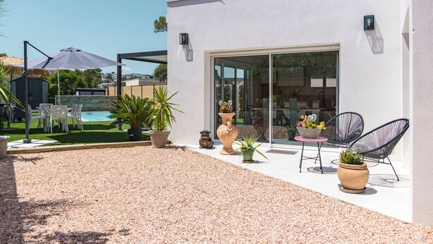 En moderne udendørs terrasse med swimmingpool, siddepladser og plantekasser.