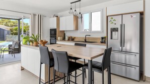 Et moderne køkken med en central ø, rustfrie stålapparater og et spiseområde med stole.