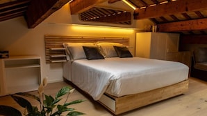 A bedroom with a wooden bed frame, a headboard, a bedside table, and a plant.