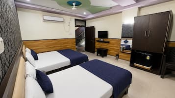 Habitación de hotel con dos camas, un televisor, un escritorio, un armario y un ventilador de techo.