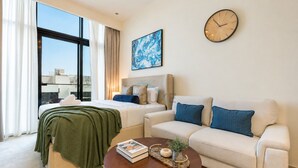 Ein modernes Hotelzimmer mit einem Bett, einem Sofa, einem Couchtisch, einer Uhr und einem großen Fenster.