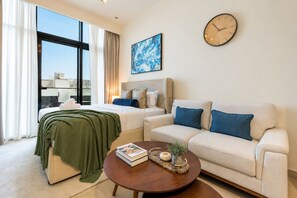 Ein modernes Hotelzimmer mit einem Bett, einem Sofa, einem Couchtisch, einer Uhr und einem großen Fenster.