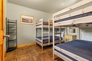 A bunk bed room with a metal shelf, a framed picture on the wall, and a bedside table.