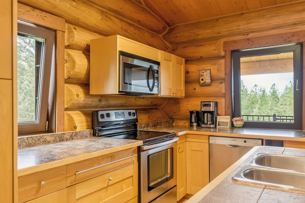 A wooden cabin kitchen with a microwave, stove, and dishwasher.
