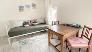 Een kamer met een bed, een tafel en stoelen. Er zijn wanddecoraties en een raam.