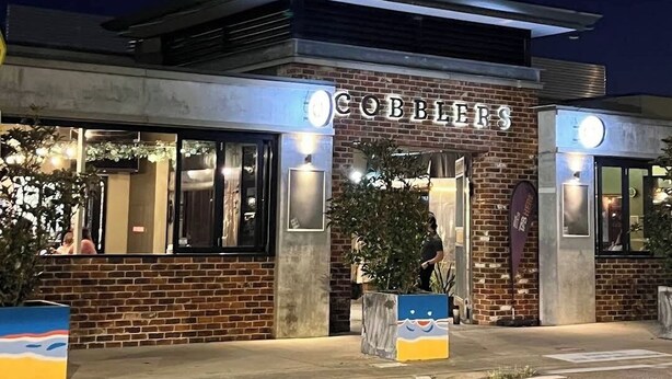 Ein Gebäude, an dem nachts ein Schild mit der Aufschrift 'COBBLES' angebracht ist.